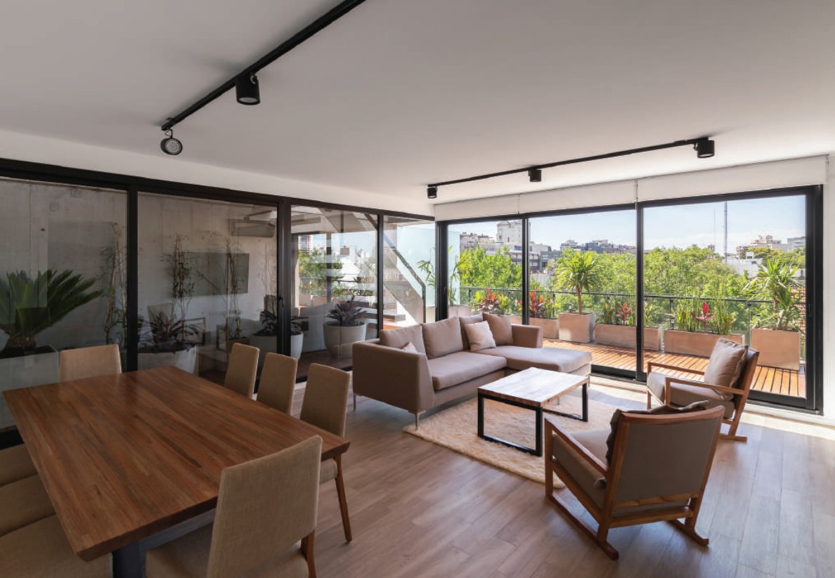 Living con grandes ventanales de aluminio que dan a una terraza